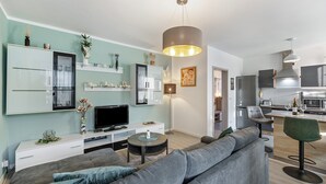 A modern living room with a sofa, TV, and a dining area with a bar. - Holiday Home 'Radlerrast' with Private Garden and Wi-Fi (Weißenfels)