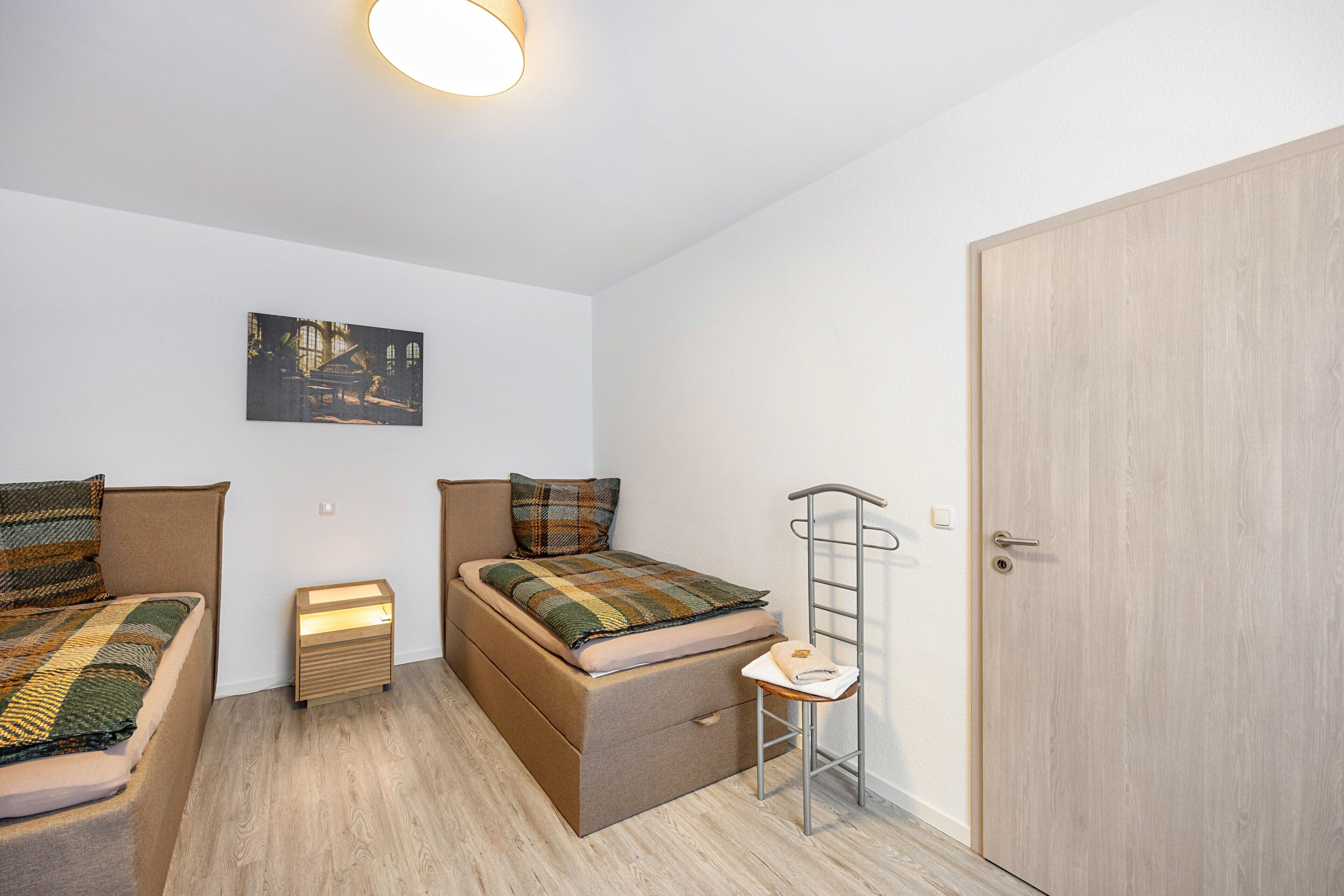 A small, well-lit room with two beds, a ladder, a small table, and a door.