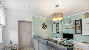 A modern living room with a grey sofa, a TV, and a dining table. - Holiday Home 'Radlerrast' with Private Garden and Wi-Fi (Weißenfels)
