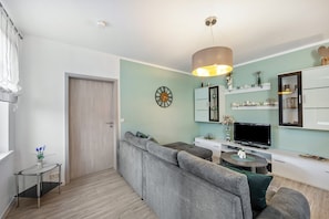 Una sala moderna con un sofá gris, un televisor y una mesa de comedor.