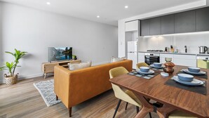 Un salon moderne comprenant un canapé, une table à manger et un coin cuisine.