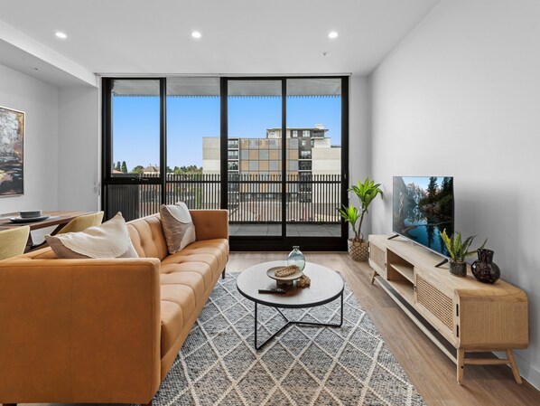 Una sala de estar moderna con sofá, mesa de centro y mueble para televisión.
