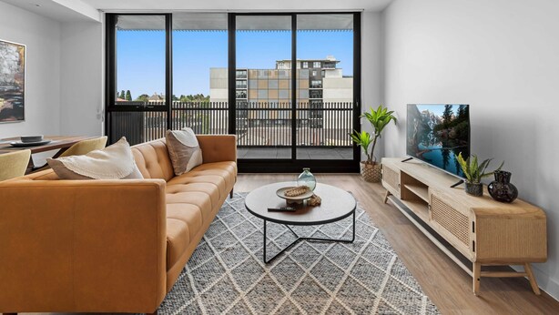 Un salon moderne avec un canapé, une table basse, un téléviseur et un balcon.