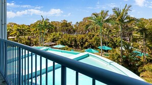 Un espace piscine offrant une vue sur un paysage tropical, avec des palmiers et un ciel dégagé.