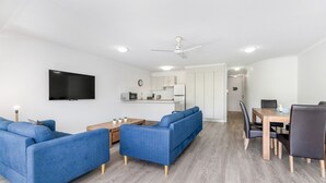 Un salon moderne avec un ensemble de canapés, une table à manger et un coin cuisine à l’arrière-plan.