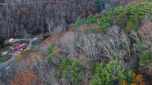 A mountainous landscape with autumn foliage, a road, and a red building with a white roof. - Romantic Geodesic Dome • Hot Tub Under the Stars (pipestem)