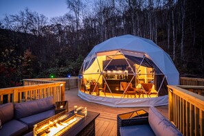 Una tienda de forma abovedada con zona de bar, terraza de madera y asientos al aire libre.