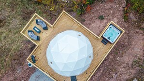 An aerial view of a deck with a central dome structure, a hot tub, and a seating area with a table and chairs. - Romantic Geodesic Dome • Hot Tub Under the Stars (pipestem)