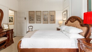 A neatly arranged bedroom with a large bed, a wooden dresser, and a chair. - Eclectic Art Deco Apartment in Great Location (Sydney)