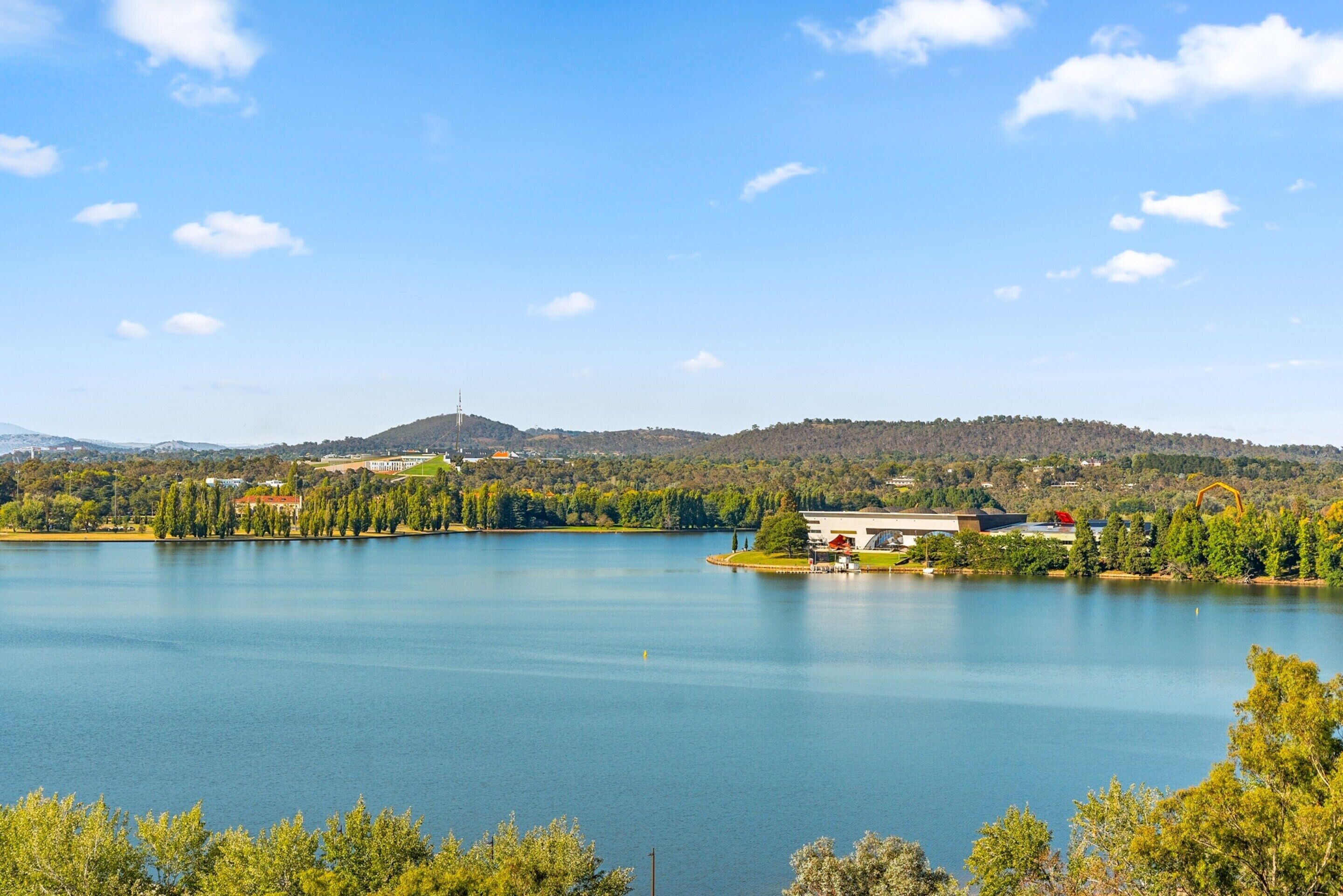 A lake with a small island, surrounded by trees and hills.