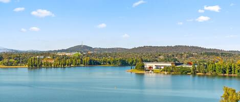 A lake with a small island, surrounded by trees and hills.