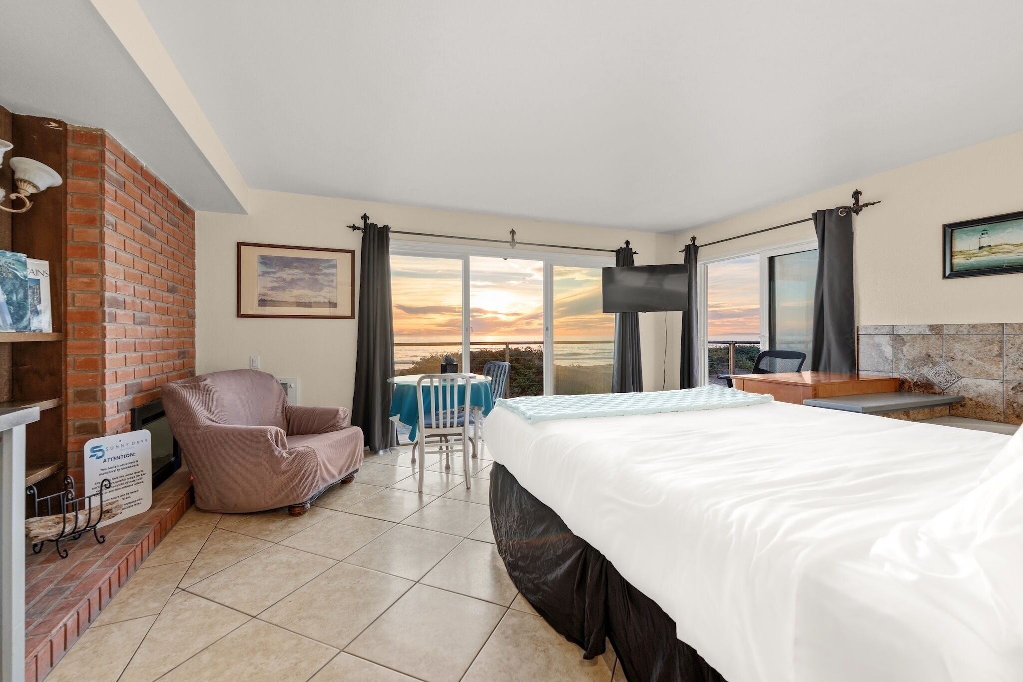 A hotel room with a bed, a chair, a table, and a TV.