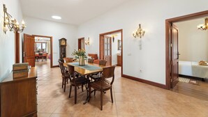 A spacious dining area with a wooden table and chairs, a chandelier, and a clock on the wall. - Refugio del Volcán by Tropical Host (Uga)