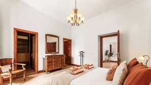 A bedroom with a bed, wooden furniture, a dresser, a mirror, and a chandelier. - Refugio del Volcán by Tropical Host (Uga)