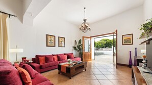 A living room with a red sofa, a wooden coffee table, and a chandelier. - Refugio del Volcán by Tropical Host (Uga)