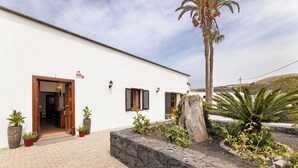A building with a white exterior, wooden doors, and a stone pathway leading to the entrance. - Refugio del Volcán by Tropical Host (Uga)
