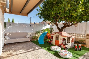 A play area with a slide, a playhouse, and a sofa.