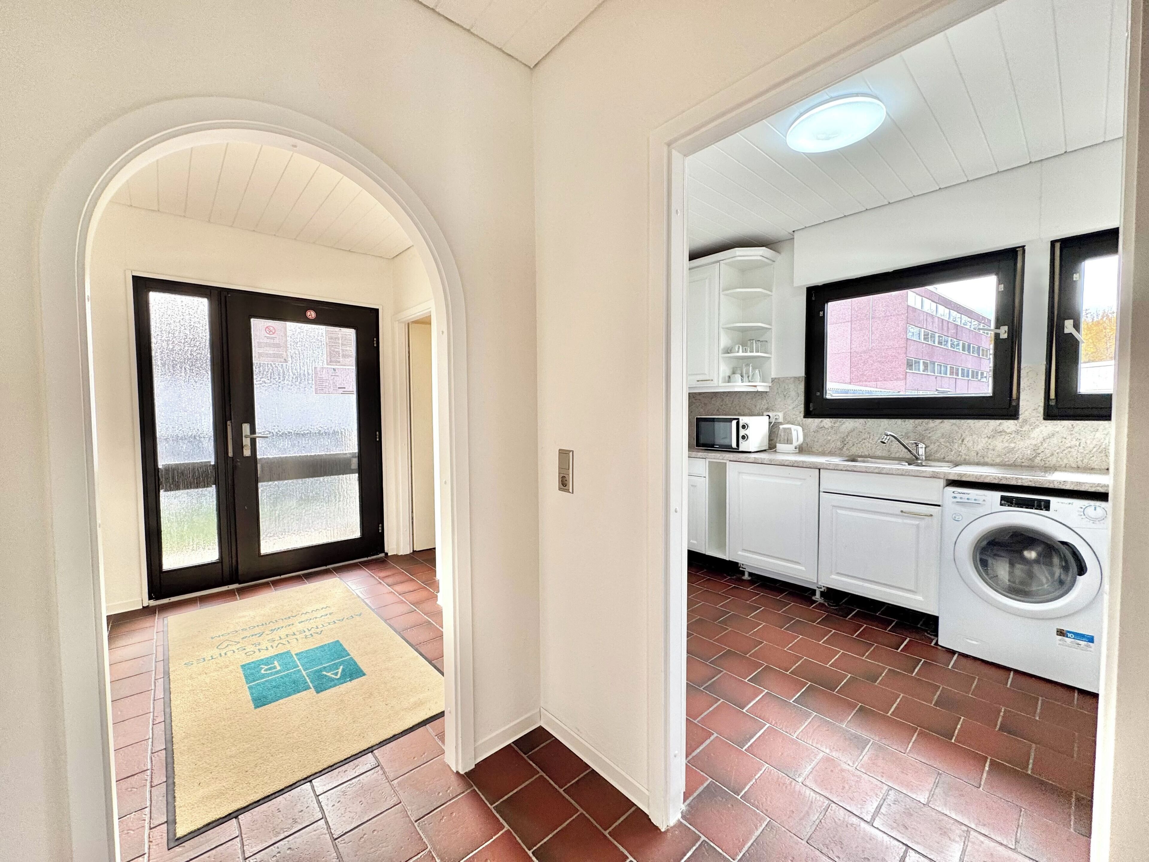 A compact kitchen with a washing machine, a microwave, and a sink.
