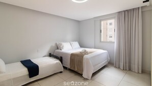 Un dormitorio con dos camas, una ventana con cortinas y una lámpara en el techo.