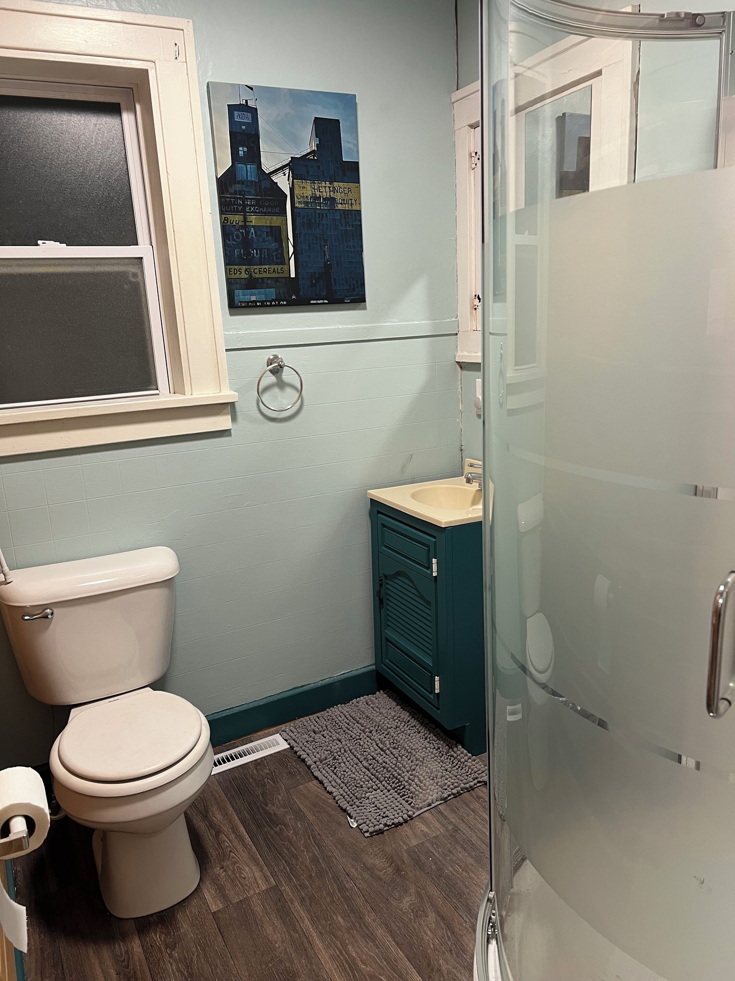 Un baño pequeño y funcional con inodoro, lavamanos y cabina de ducha de vidrio.