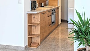 Eine moderne Küche mit Holzschränken, einem eingebauten Backofen und einer Edelstahl-Dunstabzugshaube.