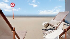Vista de la playa con dos sillas reclinables y un letrero de no estacionamiento.