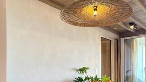 Una sala moderna con sofás redondos y con textura, una mesa redonda central con un cuenco de frutas y una gran lámpara colgante de fibra.