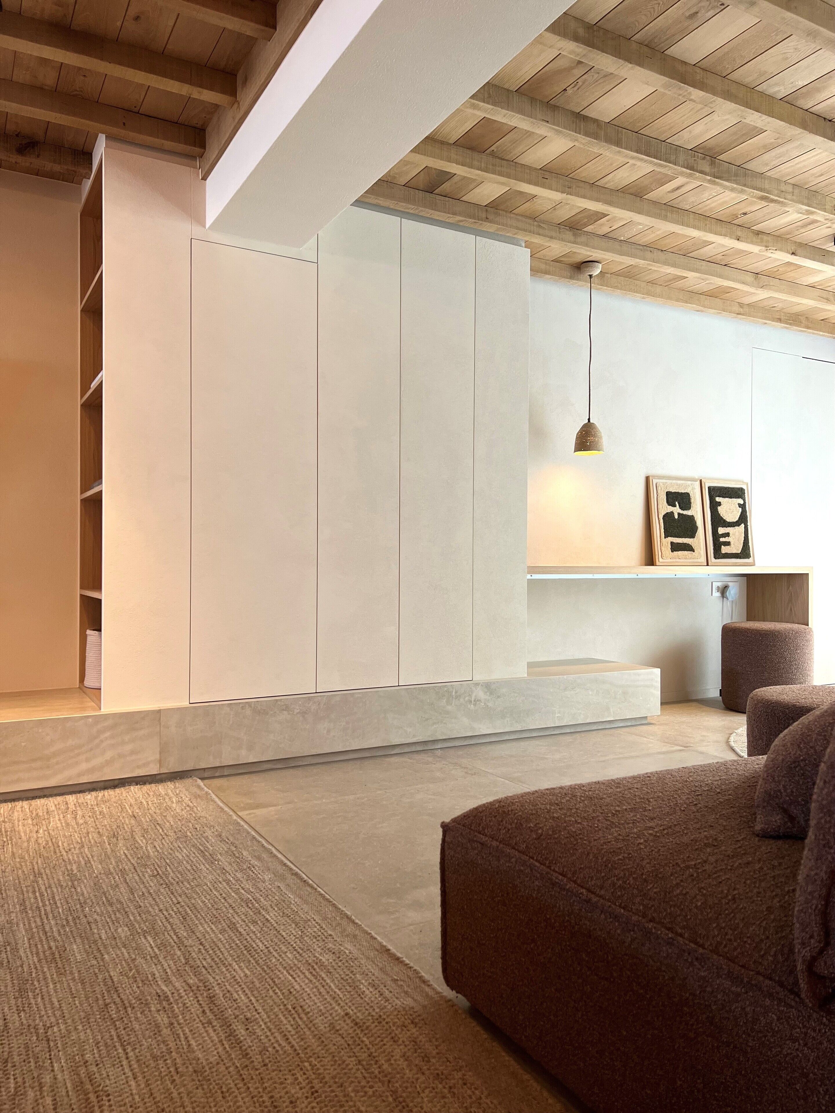 Un salon moderne avec un grand canapé marron, une basse table en bois et une bibliothèque intégrée blanche.