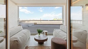 Una sala de estar moderna con un ventanal amplio, una mesa de centro redonda y dos sofás.