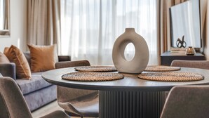A modern living room with a round table, two chairs, a decorative vase, and a sofa with cushions. - Center 1-bed With Sauna, Gym, BBQ & Parking (Canberra)