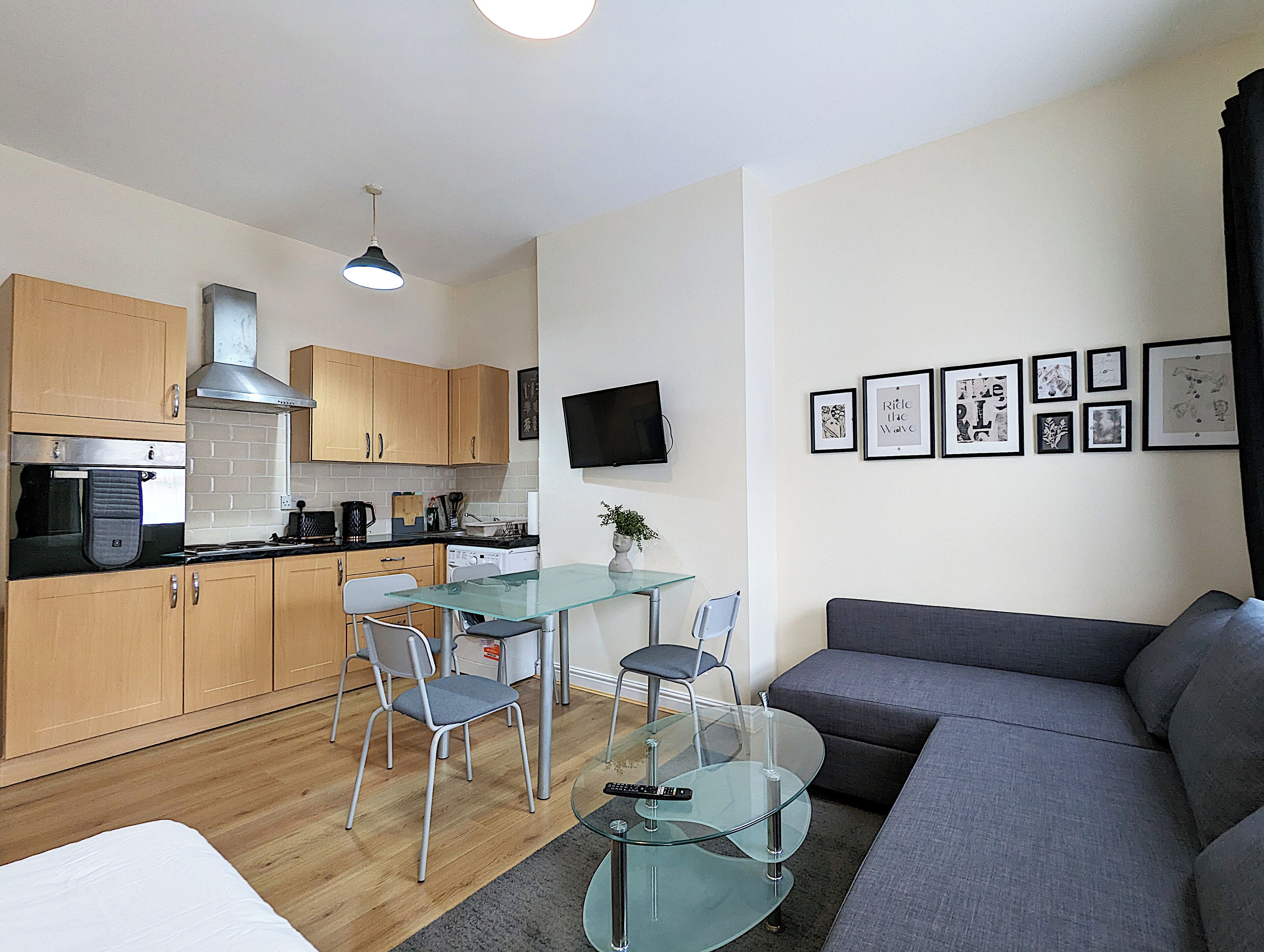 Un espace de vie compact comprenant un coin cuisine, un coin repas et un espace détente avec un canapé et des fauteuils.