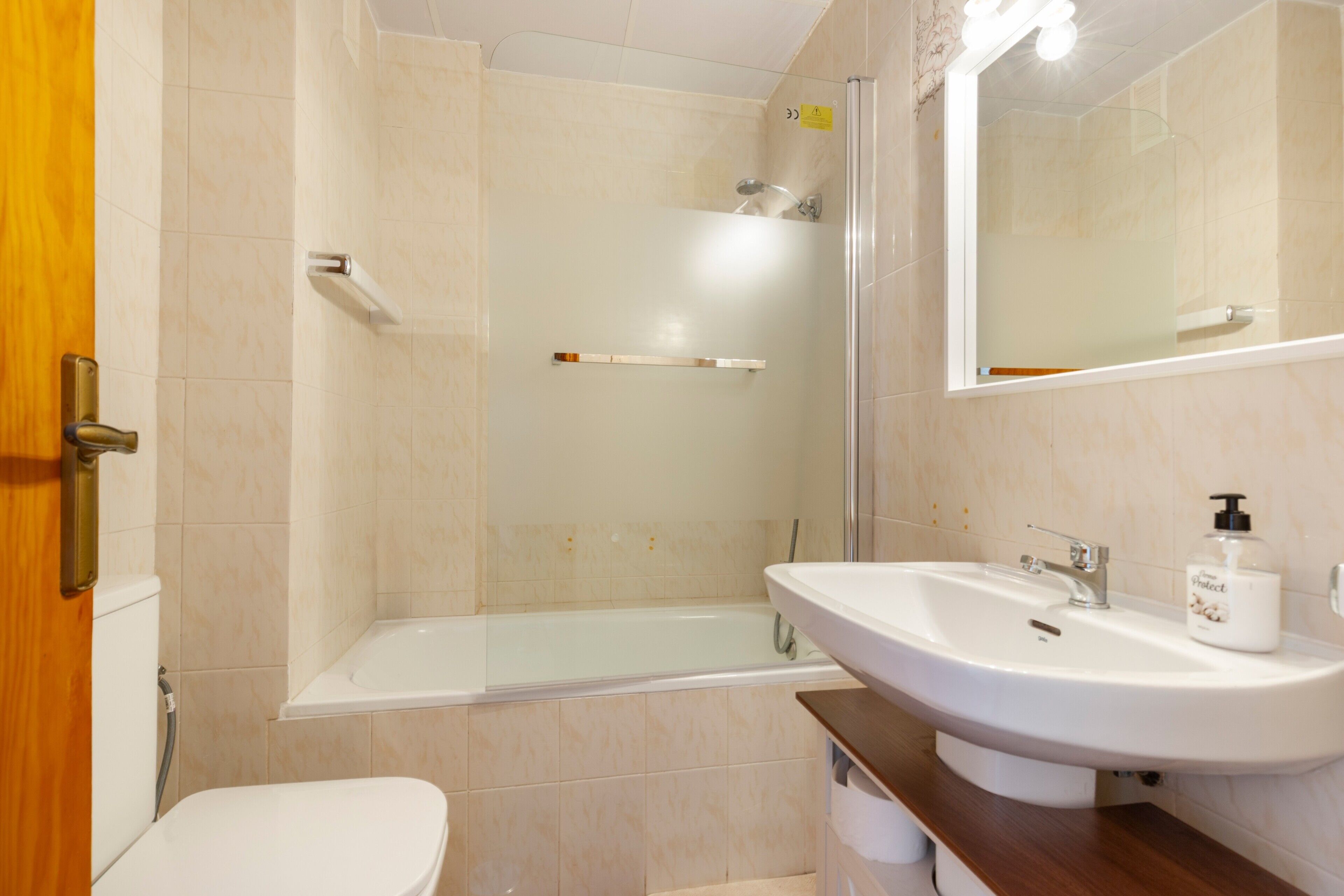 A bathroom with a bathtub, a toilet, a sink, and a mirror.