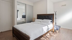 A bedroom with a large bed, a wardrobe, and a coat rack. - Cosy Kambah 1 Bedroom Near Shops & Parks (Canberra)
