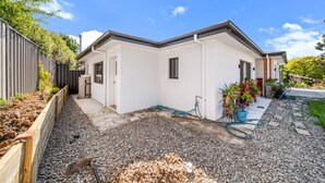 A modern house with a white exterior, a gravel driveway, and a wooden fence. - Cosy Kambah 1 Bedroom Near Shops & Parks (Canberra)