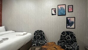 A hotel room with a bed, two chairs with a geometric pattern, a small wooden table, and three framed pictures on the wall. - Central Stay (İstanbul)