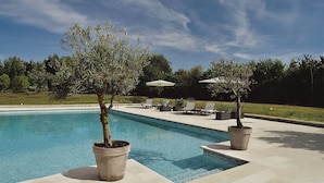 A swimming pool with potted trees, lounge chairs, and umbrellas. - Manoir de Plaisance (Benon)