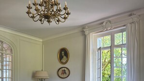 A classic room with a tufted sofa, a wooden coffee table, and a chandelier. - Manoir de Plaisance (Benon)
