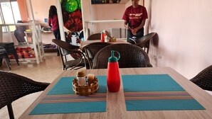 A wooden table with two teal placemats, a red water bottle, and a wooden tray with a jar and a container. - The Junction Resort Marigat (Marigat)
