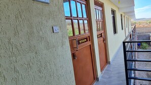 A building with a balcony, a door labeled "WISDOM," and a small outdoor area with a person working. - The Junction Resort Marigat (Marigat)