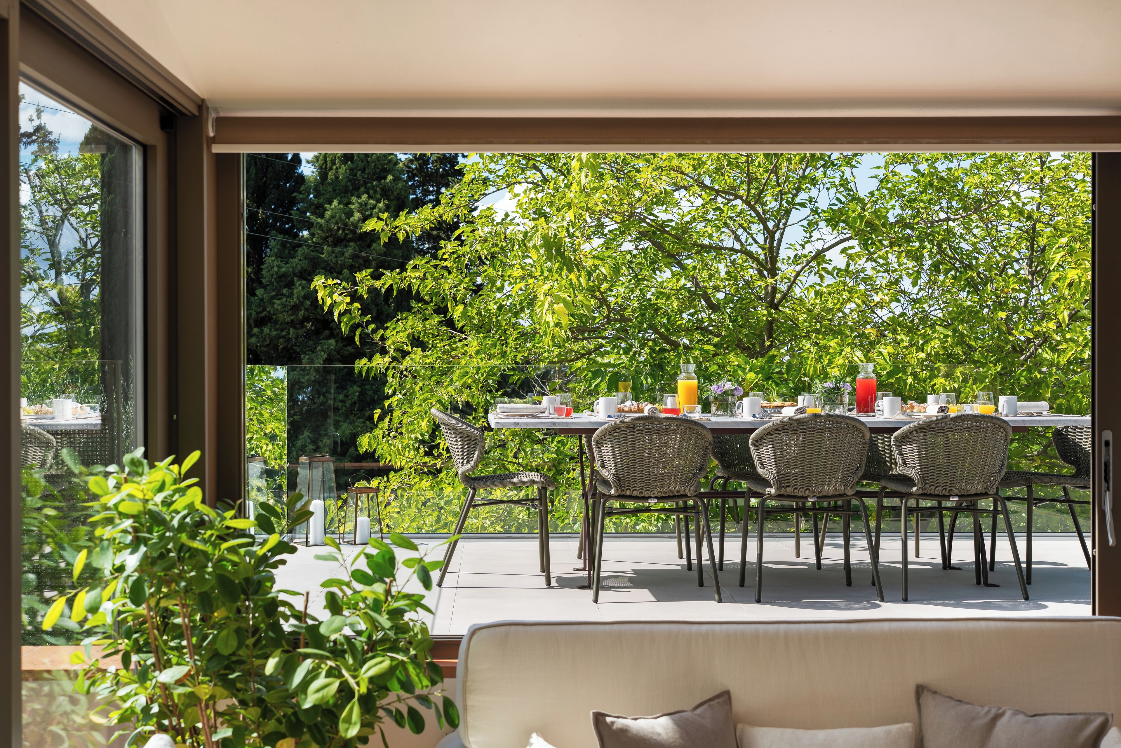 Een buiten eethoek met een tafel voor vier personen, omringd door rieten stoelen, met uitzicht op een weelderige tuin.
