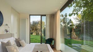 A modern bedroom with a large bed, a view of a garden, and a green chair. - House in the heart of Chianti, with 4 bedrooms, each with a private bathroom. (Toscana)