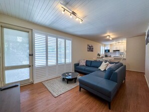 A living room with a sectional sofa, a coffee table, and a dining area with a kitchen in the background. - Bright & Airy Adelaide Retreat With Courtyard (Adelaide)