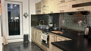 Una cuina moderna amb sòl de rajoles fosques, armaris de fusta, un taulell negre i una petita illa.