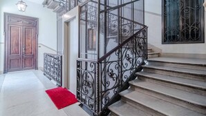 A staircase with ornate metal railings, a wooden door, and a red rug. - GuestHost - Cozy Central Apartment in Turin (Turin)