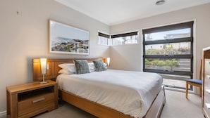 Ein Schlafzimmer mit einem Bett, Nachttischen, einer Kommode und einem großen Fenster mit Blick.