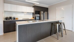 Eine moderne Küche mit dunklen Schränken, einem Edelstahl-Kühlschrank, einer Mikrowelle und einer Kaffeemaschine.