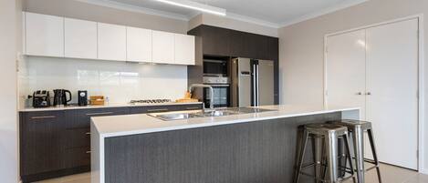Una cucina moderna con mobili scuri, un frigorifero in acciaio inossidabile, un forno a microonde e una macchina da caffè.