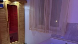 A spa room with a hot tub, a wooden cabinet, and a window with sheer curtains.