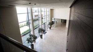 Un'ampia area interna con grandi finestre, piante in vaso e pavimento piastrellato.