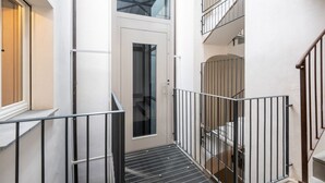 A multi-level interior with a staircase, metal railings, and a door leading to another room.